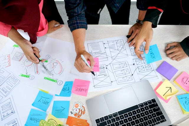 A team working on wireframes and sticky notes, representing the brainstorming and planning phase of user interface design.