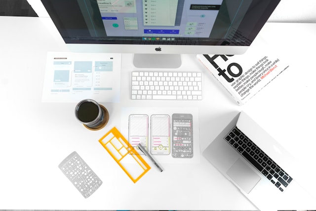 A workspace with wireframes, design tools, and a computer, illustrating the process of creating mobile user interface designs.